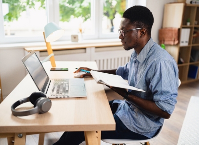 Student studying at laptop with notebook